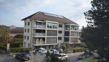 4 story building, solar panels on the roof, balconies, parking lot