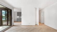 une photo d'une maison moderne avec des murs blancs, des sols en bois et une grande entrée ouverte sur la cuisine / a picture of a modern home with white walls, wooden floors, and a large open entran