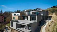 Modern house, multiple levels, balconies, gray brick, glass windows, under construction