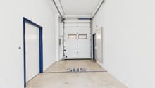 Empty storage room with concrete floor, white walls, blue trims on doors, two doors on left, two doors on right