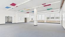 Empty room, white walls, gray carpet, multiple large windows, white column in the center, square ceiling tiles
