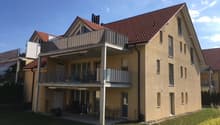 3-story apartment building with beige exterior, red tile roof, and balconies on each floor.