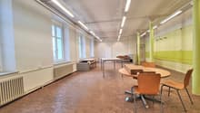 empty office with wooden floor, white walls, radiators, large windows, round and rectangular tables, chairs