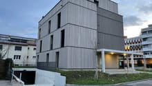 modern building, gray exterior, multiple windows, entrance with canopy, underground parking