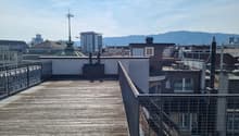 Wooden deck, metal railings, city view, mountains in the distance
