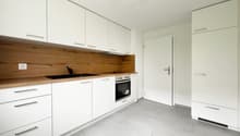 White kitchen, wooden counter, white appliances, large windows