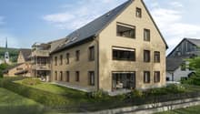 2 story building, beige color, raised ground floor, multiple balconies, solar panels