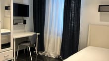 small bedroom with desk, chair, bed, and mounted TV