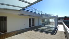 covered balcony with wooden floor, glass walls, metal railings