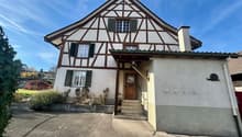 3 story house, white walls, brown trim, green windows, driveway in front