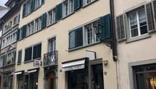 4 story beige building, green shutters, street lamp, entrance to shops