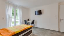 bedroom with bed, desk, chairs, television, curtains, tiled floor