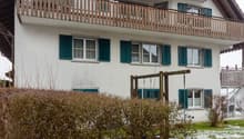 2-story house, white exterior, brown roof, green shutters, wooden balcony