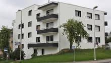 modern white building, 3 floors, balconies, green grass, street lights