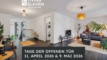 Modern open plan room with white walls, hardwood floors, contemporary furniture, large windows, appliances, and plants