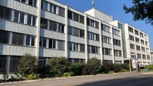 4 story apartment building, white walls, multiple windows, shrubs in front