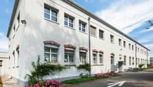 Two story white house with brick detail, multiple windows, bicycles parked in front.
