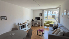 living room with dining area, wooden floor, white walls, large windows, round table, chairs, couch, side table, desk, chair, monitor, lamp, rug, books, picture frames