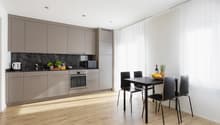 modern kitchen, wooden floor, kitchen island, gas stove, microwave, dishwasher, sink, grey cabinets, dining table with 4 chairs