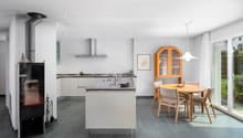 modern kitchen with island, fireplace, dining area, wooden table and chairs, glass door to garden