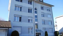 apartment building, white exterior, brown roof, multiple windows, glass door, garage