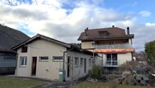 2 story house, brown roof, balcony, green trash bin, garden, fence