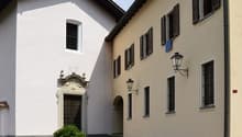 Two story building, brick roof, two entrances, brown wooden door, stone wall, large windows, brown grass, potted plant