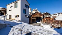 Modern white house with garage, set in a snowy mountainous village