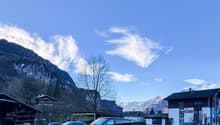Mountainous area with a building, a shed, and a parking lot with several cars parked
