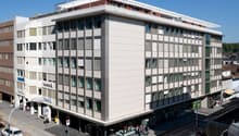 A building with multiple floors, several windows and multiple signs such as Helvetia and Allianz