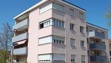 pink building, multiple balconies, two cars parked in front