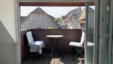 Balcony with table and chairs, wooden floor, open sliding doors, view of the city