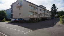 multi-family house, beige facade, balcony on the 2nd floor, street with parked cars
