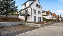 2 story white house, black windows, balcony, driveway, trees