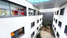 White exterior building, large windows, balcony on second floor, internal courtyard, small trees, tiled flooring