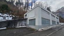 Modern building, white exterior, grey brick walls, glass windows, garage entrance, concrete walkway
