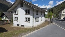 2 story house, white exterior, multiple windows, chimney, located on a street with mountains in the background