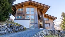 wooden exterior, large windows, stone wall, paved driveway, mountain view