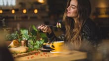 A table with food and drink, a woman eating with a fork