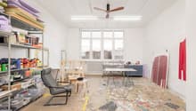 large room, white walls, ceiling fan, shelves with art supplies, tables, chairs, large windows, unfinished floor