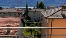 Outdoor balcony with a view of the mountains and buildings.