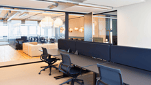 Open office with multiple cubicles, desk, chairs, glass partition walls, lamps, carpet