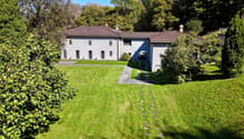 villa with garden, paved driveway, brown roof, surrounded by trees and mountains