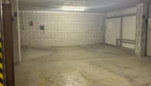 Empty parking lot with white brick wall, yellow lines, and parking bays marked