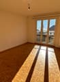 Empty room, parquet floor, white walls, sliding glass door to a balcony