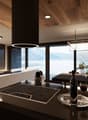 Modern kitchen with wooden ceiling, large windows providing a scenic view, induction cooktop, kitchen island with bar stools, and various decorative elements