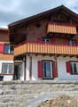 2 story house, wooden exterior, red shutters, balconies, stone foundation
