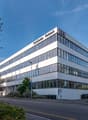 TechCenter Reimach is a 4 story white office building with glass windows, located on the side of the road