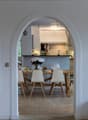 open floor plan with dining area and kitchen, white walls, brick floor, modern furniture, two windows with niches, stairs