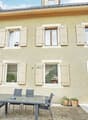 2 story house, beige exterior, white shutters, glass table, chairs, potted plants, entrance
